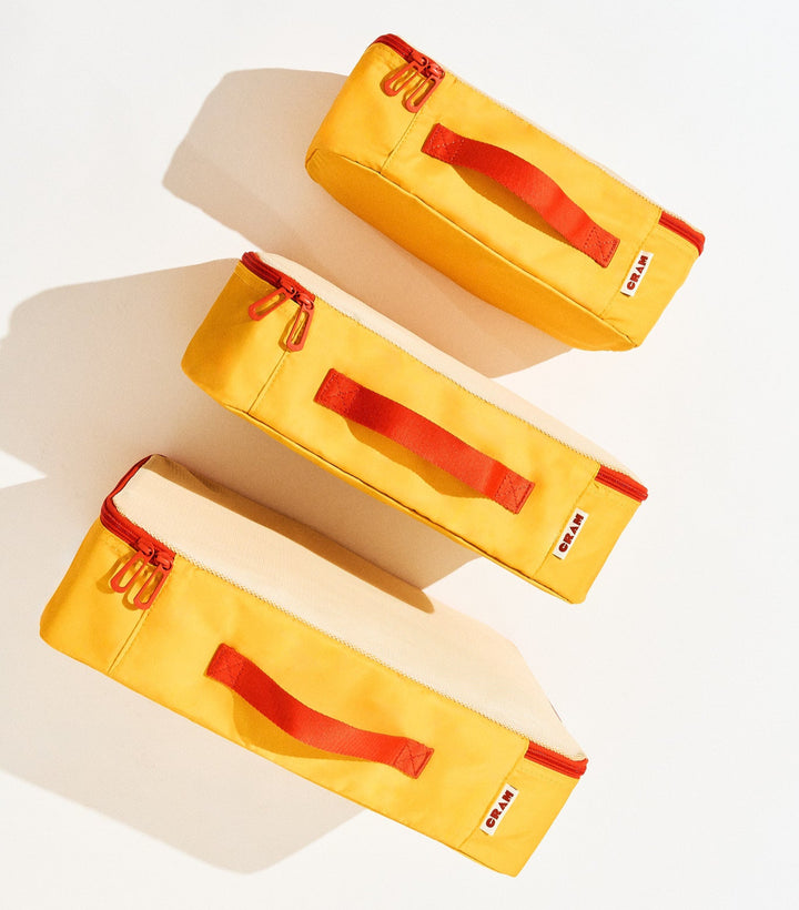 3 sizes of sunrise yellow Cram packing cubes suitcase organizer standing upright in front of each other, top down view