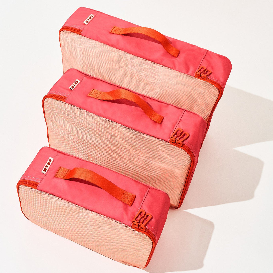 3 sizes of bloom red Cram packing cubes suitcase organizer standing upright in front of each other, top down view