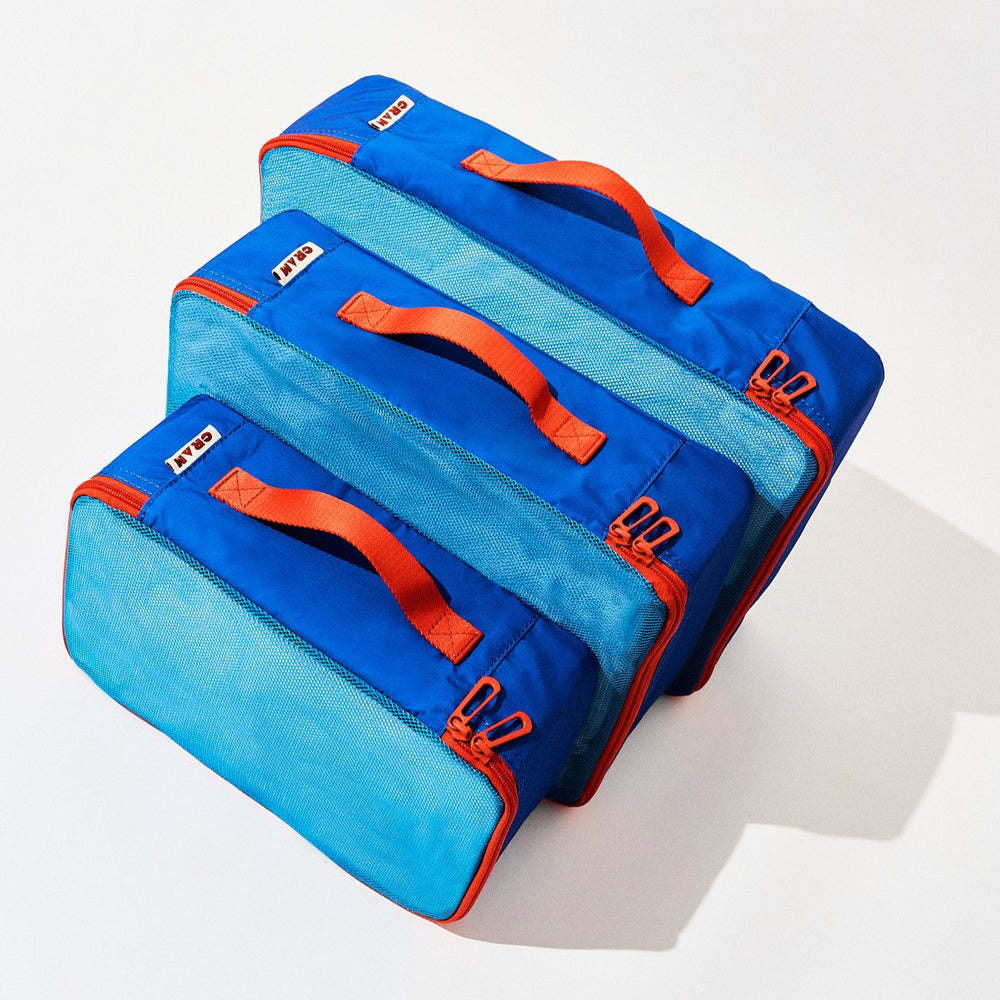 3 sizes of pacific blue Cram packing cubes suitcase organizer standing upright in front of each other, top down view