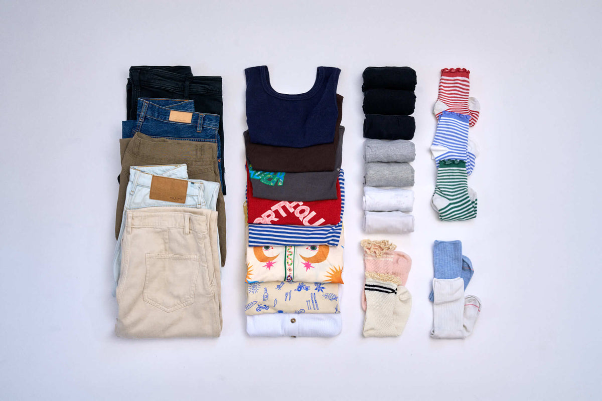 Flat lay of what fits in 3 Cram packing cubes: 8 shirts, 5 pairs of pants, 7 pairs of socks and 7 pairs of underwear